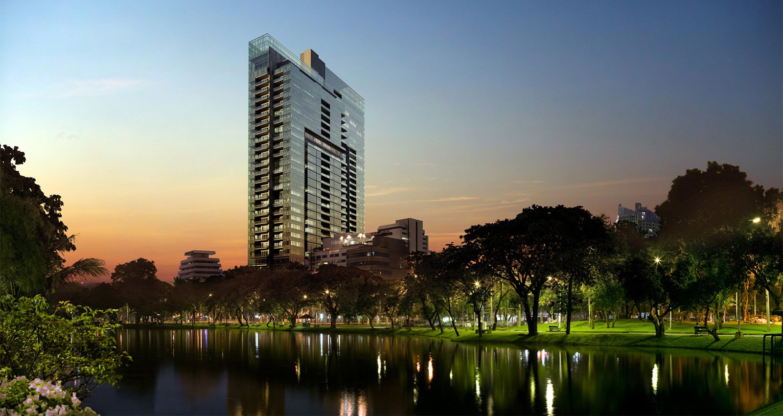 185 Rajadamri tower at sunset over a park lake